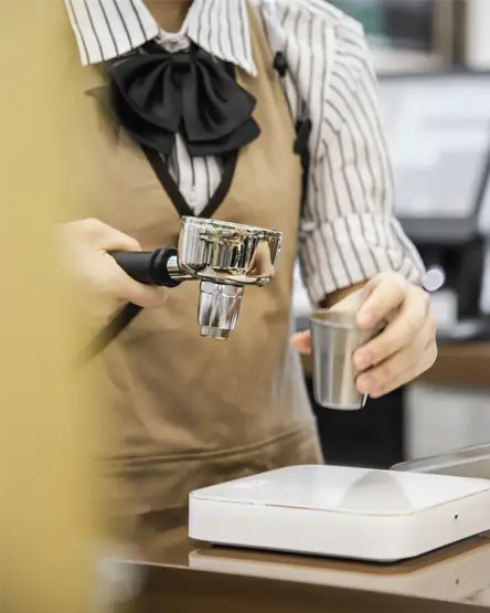 A barista measuring ingredients with a jigger at the brewing bar
