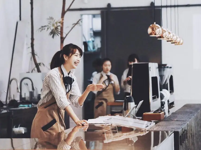 A smiling Chi Cha San Chen barista greeting a guest across the counter